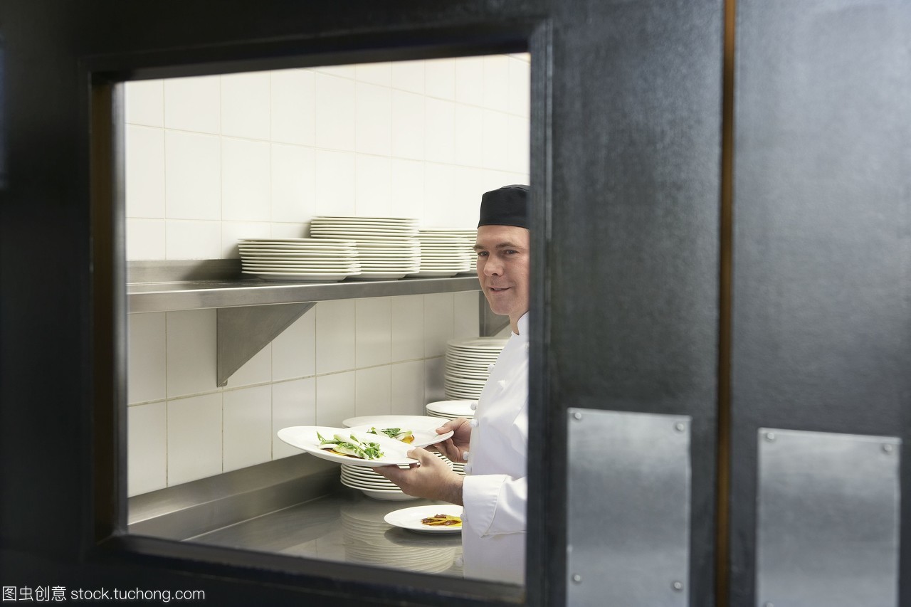 專業(yè)廚房中的熱情服務(wù) 微笑廚師與精美正餐